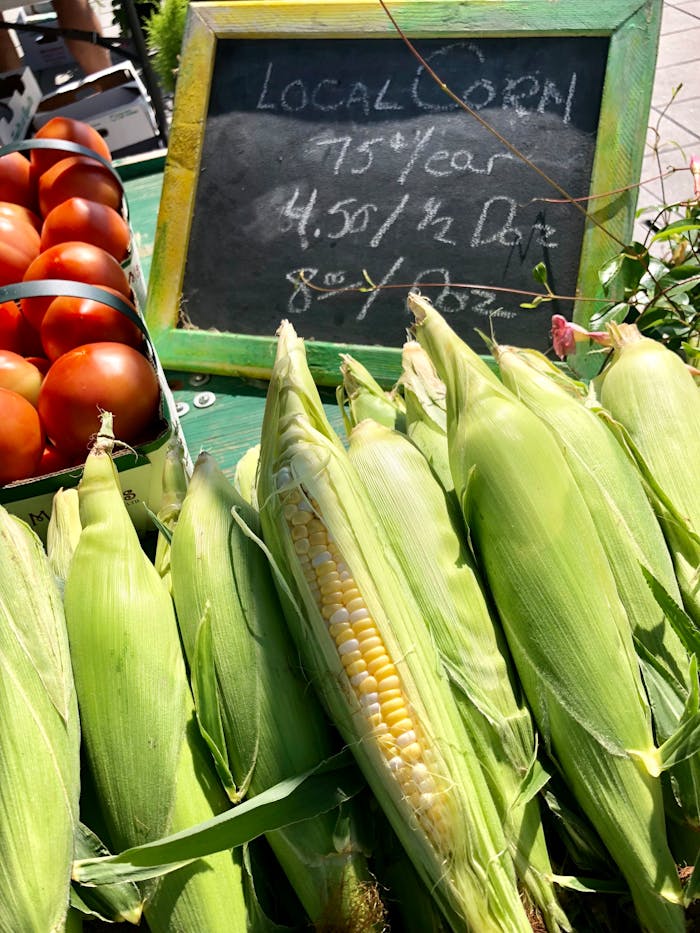 Close-up of fresh local corn and tomatoes at a farmers market in Kingston, ON, Canada.