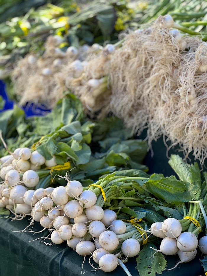 Close-up of fresh radishes with roots and greens on display at a market.